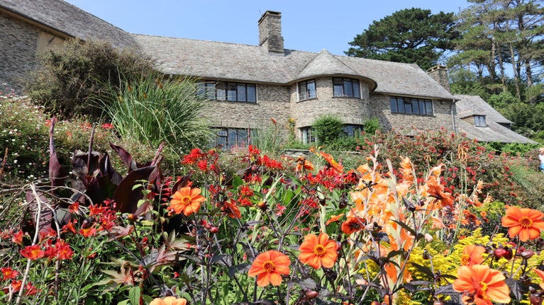 Flower border in front of the house full of red and orange flowers in summer at Coleton Fishacre, Devon